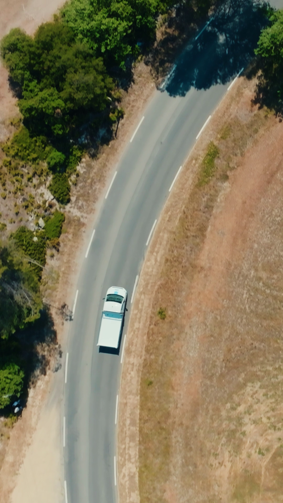 Vue aérienne verticale — suivi d'un véhicule sur route sinueuse filmé par drone, ORYGEN FILMS